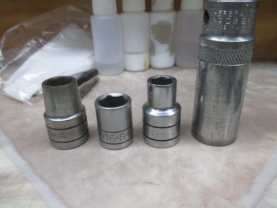 Four socket wrenches and several small plastic bottles on a tiled surface