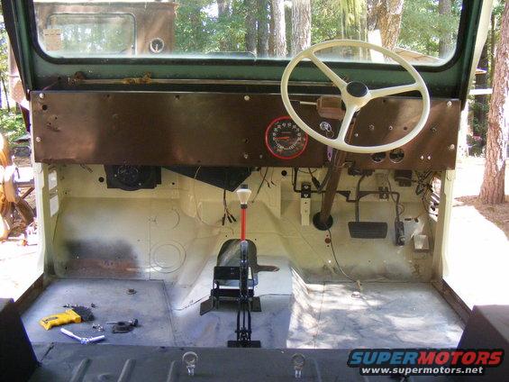 Interior of a Jeep CJ, showing dashboard, steering wheel, pedals, and floor