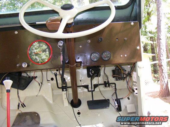 Dashboard with steering wheel, gauges, pedals, and wiring. A red-ringed speedometer is visible