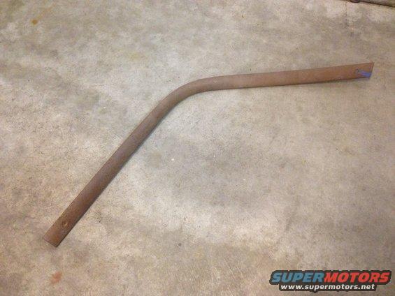 Rusted metal rod with a bend, lying on concrete floor