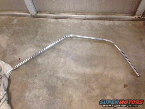 Chrome trim piece with a bent section, lying on a concrete floor