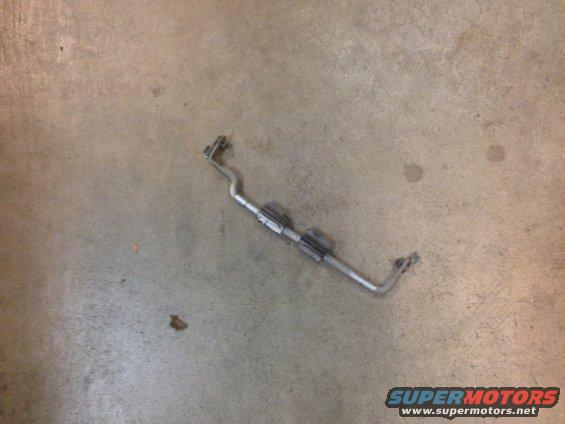 Metal bar with two brackets attached, lying on a concrete floor