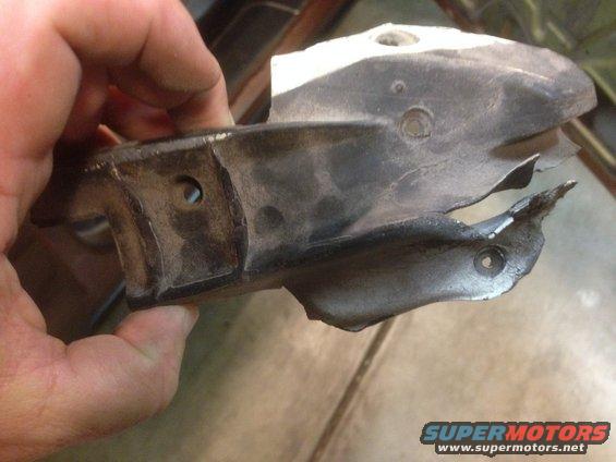 Hand holding a damaged metal bracket with mounting holes