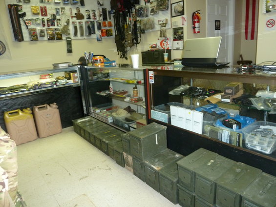 Interior of a store with display cases filled with merchandise and ammo cans stacked on the floor