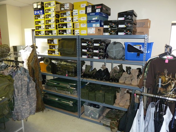 Shelves stocked with boxes, boots, camping gear, and clothing in a store
