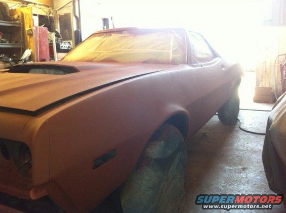 Red 1972 Ford Ranchero with hood scoop, covered in masking paper, in a garage