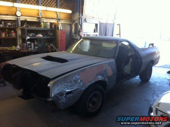 1972 Ford Ranchero project car with hood scoop, primer finish, and open doors in a garage