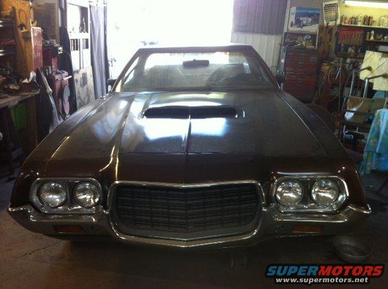 Brown 1972 Ford Ranchero front view in garage, hood scoop, chrome grille, dual headlights
