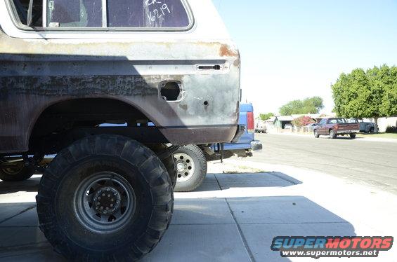 Rear quarter of a rusty 1978 Ford Bronco with large tires, parked next to another vehicle
