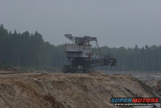 Bucket-wheel excavator in a quarry with a forest in the background