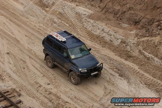 Dark blue SUV with a roof rack driving on a sandy track