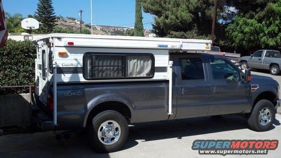 Dark gray Ford F-250 Super Duty truck with a white Grandby camper shell, side view