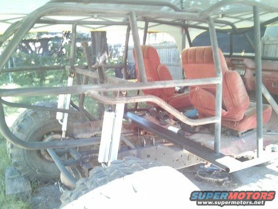 Off-road buggy frame with red bucket seats and a roll cage. Large tires visible