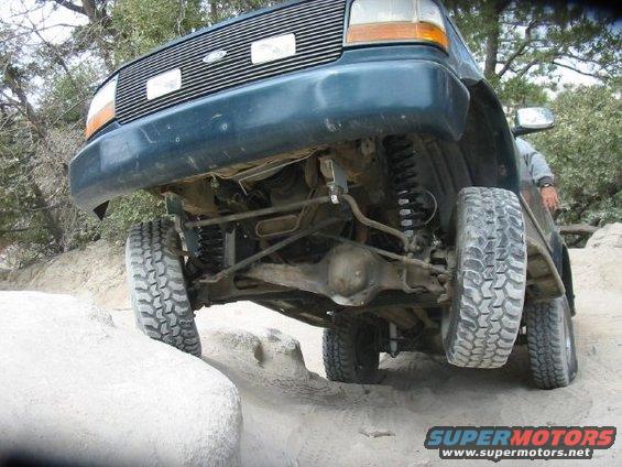 Dark green 1992 Ford Bronco front end angled up a rock, showing suspension and undercarriage