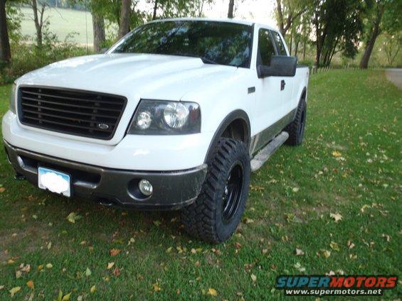 White 2006 Ford F-150 pickup truck parked on grass with trees in background