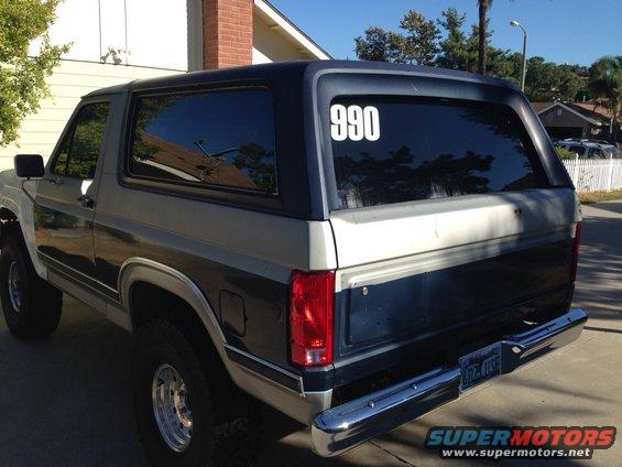 1986 Ford Bronco rear view, two-tone paint, chrome bumper, tinted windows with '990' decal