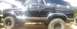 1986 Ford Bronco - This black Ford Bronco, likely from the early 1980s, is shown from the side with off-road tires.