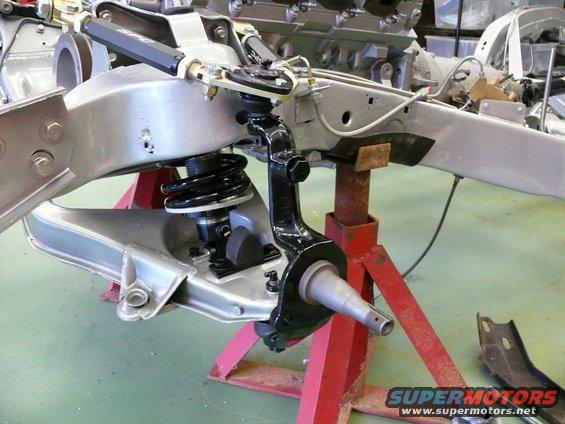 Front suspension assembly on red jack stands, with engine block in background