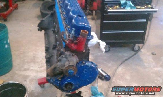Blue engine on a red stand in a garage, with a toolbox in the background