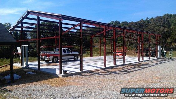 White pickup truck and other vehicles inside a metal building frame