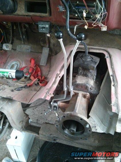 Interior of a vehicle showing the transmission tunnel with two shifter levers and transfer case components