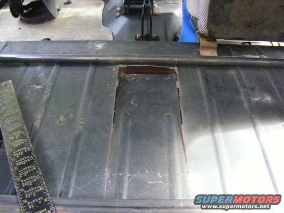 Metal floor panel with cut-out and ruler, viewed from above