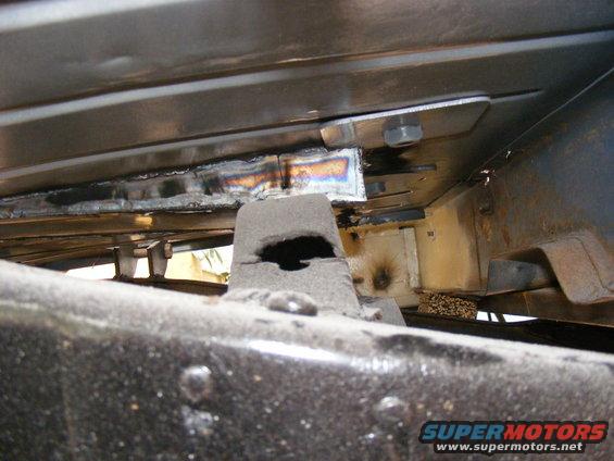 Underbody view of vehicle frame with visible welds and suspension parts