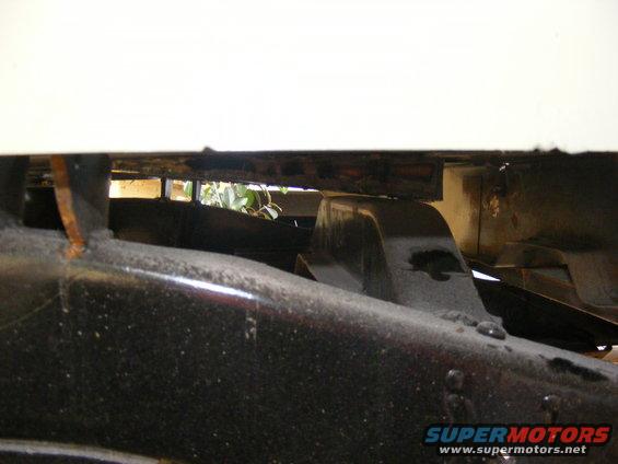 Close-up of a vehicle's frame and suspension components, showing rust and dirt