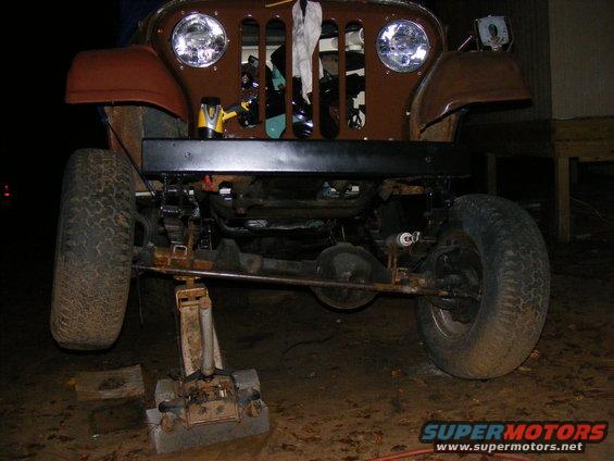 Front end of a brown Jeep CJ on a jack, showing suspension and grille