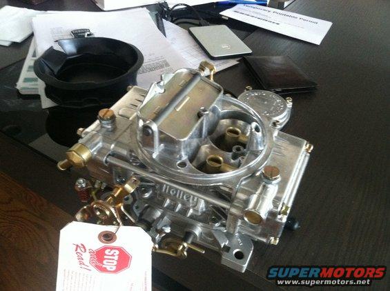Holley carburetor on a desk with papers and a wallet