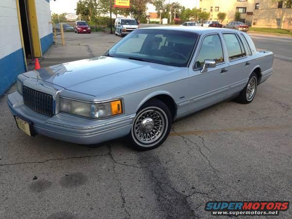 Silver Lincoln Town Car parked on asphalt. The car has chrome trim and wire wheels