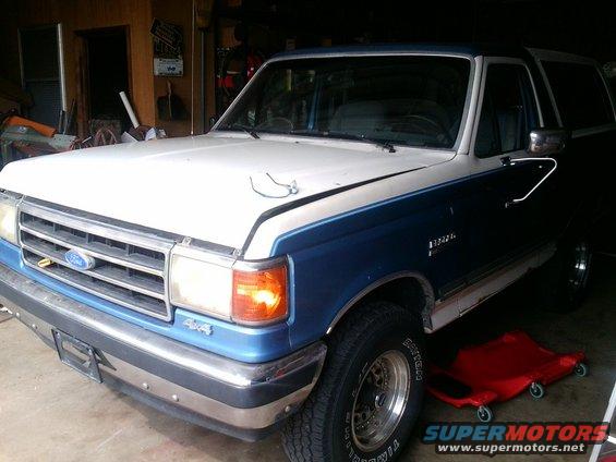 Blue and white Ford Bronco with 4x4 badge, parked in a garage