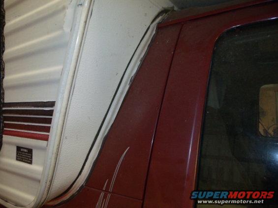 Red vehicle body panel with pinstripes next to a white camper shell with brown and red stripes