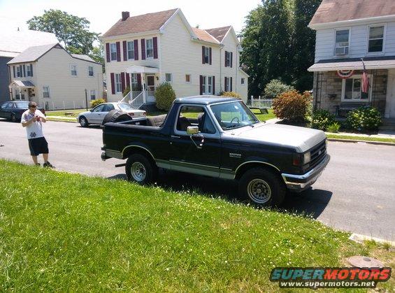 Black and silver 1990 Ford Bronco parked on a residential street, viewed from the front quarter