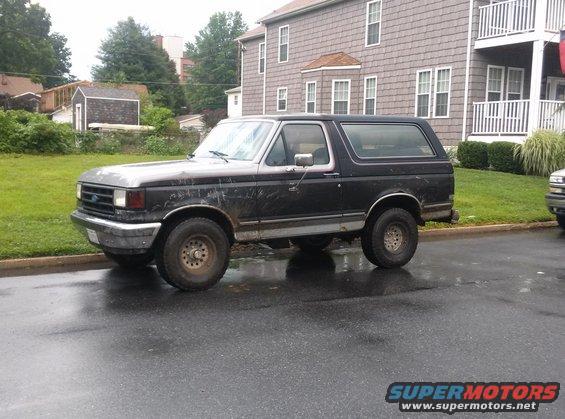 Black 1990 Ford Bronco parked on a wet street
