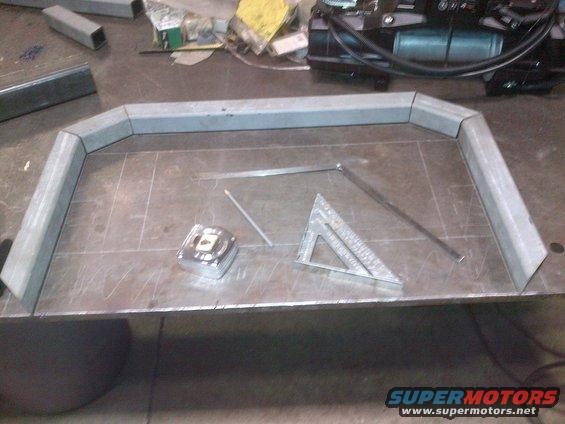 Metal frame pieces on a workbench with a tape measure and square