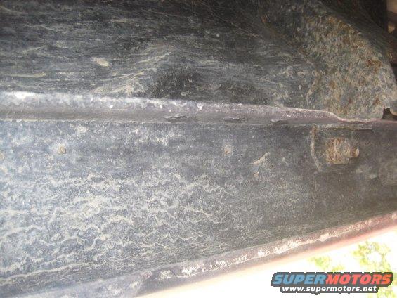 Underside frame detail with rust and dirt. Supermotors.net logo visible