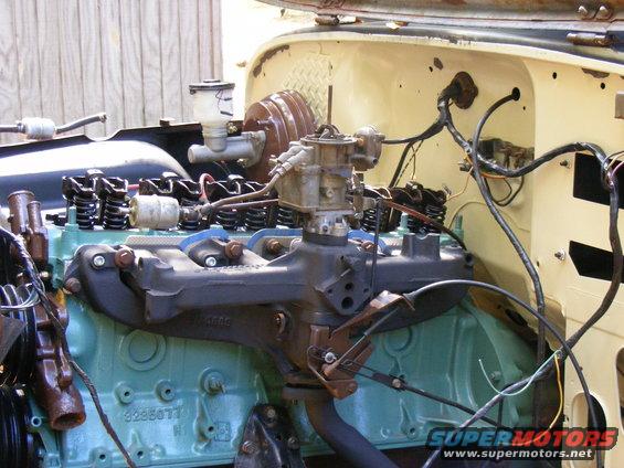 Engine bay with carburetor, brake booster, and teal engine block. Visible part number 3235077