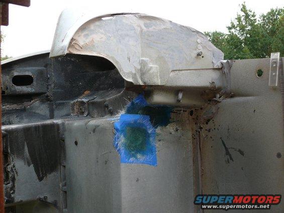 car frame with blue tape and fiberglass patch on wheel well area
