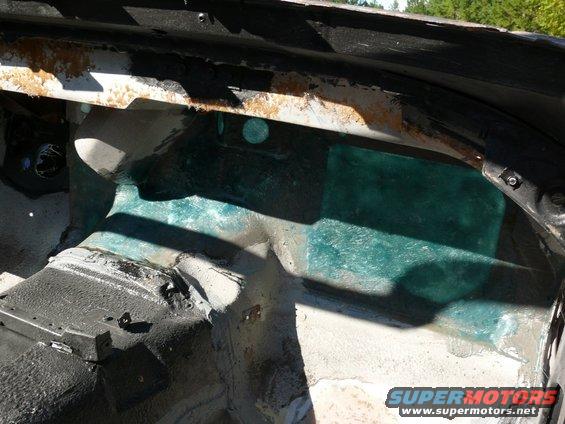 Car interior showing rust and green fiberglass repair on the passenger side floor pan