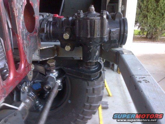 Close-up of a Jeep steering box and linkage, with a tire and suspension visible