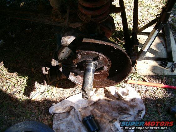 Close-up of a rusty brake rotor and hub assembly with a splined axle shaft protruding