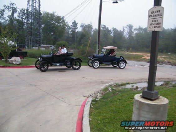 Two black 1909 Ford Model Ts driving on a road