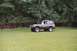 1976 Ford Bronco - 1976 Ford Bronco parked in a grassy field with trees behind it.