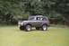 1976 Ford Bronco - A green 1976 Ford Bronco with a soft top is parked on a grassy area with trees in the background.