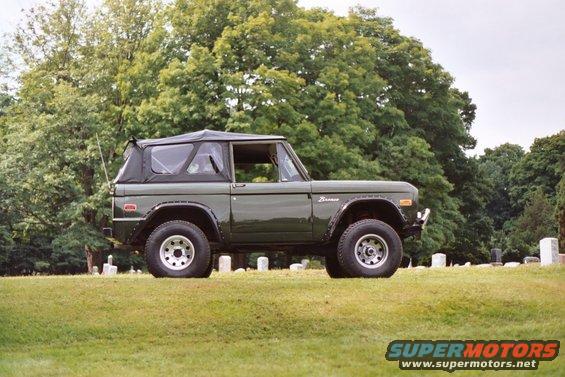 1976 Ford Bronco, dark green, soft top, parked on grass with trees and gravestones in background