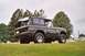 1976 Ford Bronco - Rear view of a 1976 Ford Bronco, parked outdoors in a grassy area with trees and gravestones.