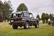 1976 Ford Bronco - A 1976 Ford Bronco is parked on a grassy field near a cemetery, with a riding mower visible to the right.