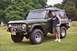 1976 Ford Bronco - A man stands next to a dark green 1976 Ford Bronco, which has a soft top and an aftermarket front bumper.