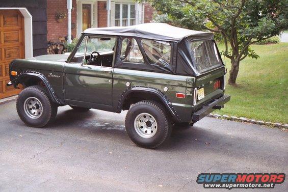 Dark green 1976 Ford Bronco with a black soft top parked on a driveway